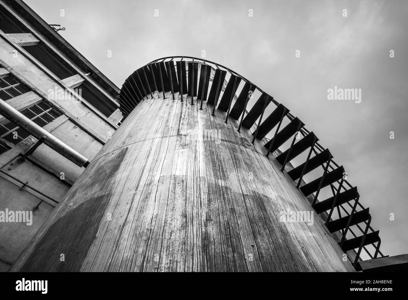 Wide angle geometrical black and white view of a large silo with a spiral staircase Stock Photo