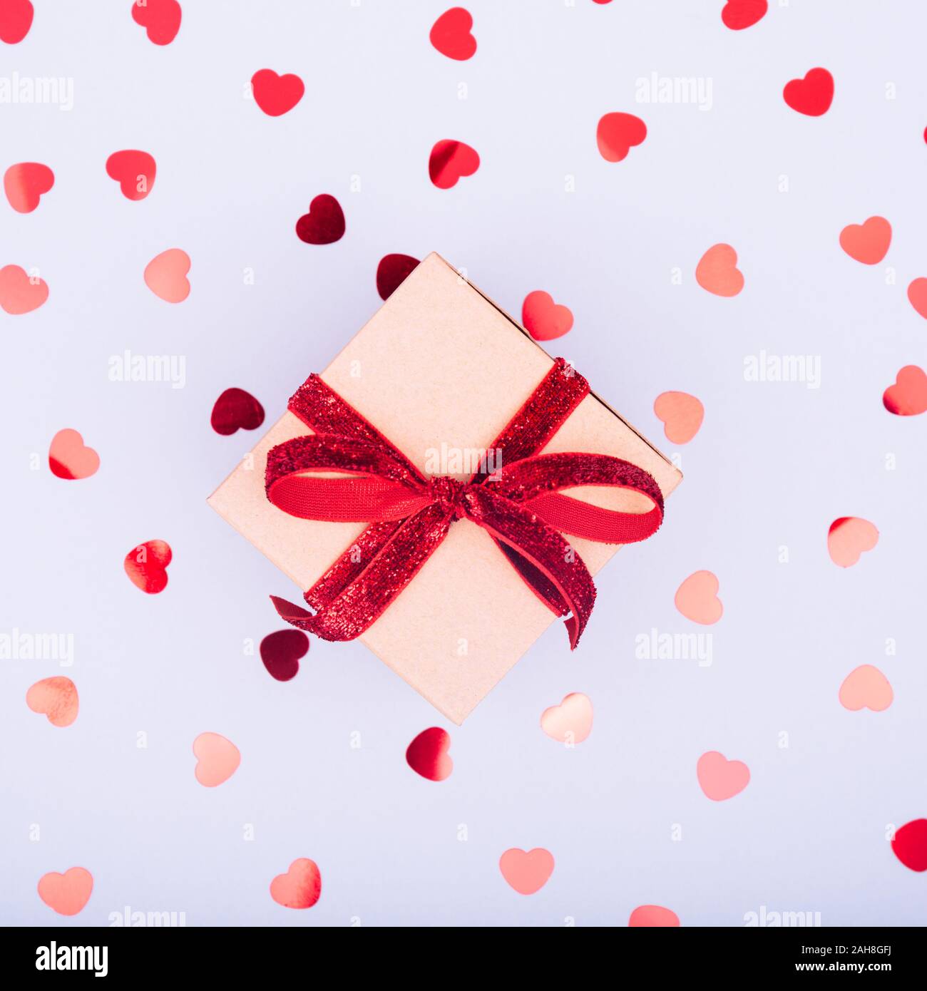 Craft box with red ribbon bow and glitter heart confetti. Valentine day ...