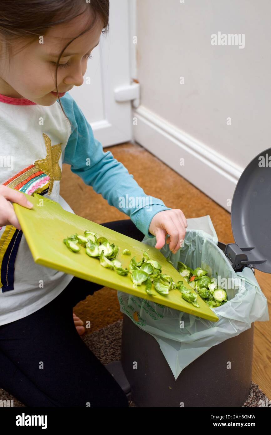 Young girl putting sprout peeling into food waste bin Stock Photo