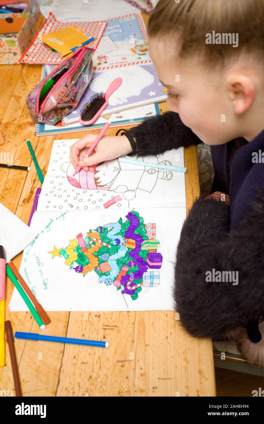 young girl colouring in Christmas scenes at the table Stock Photo