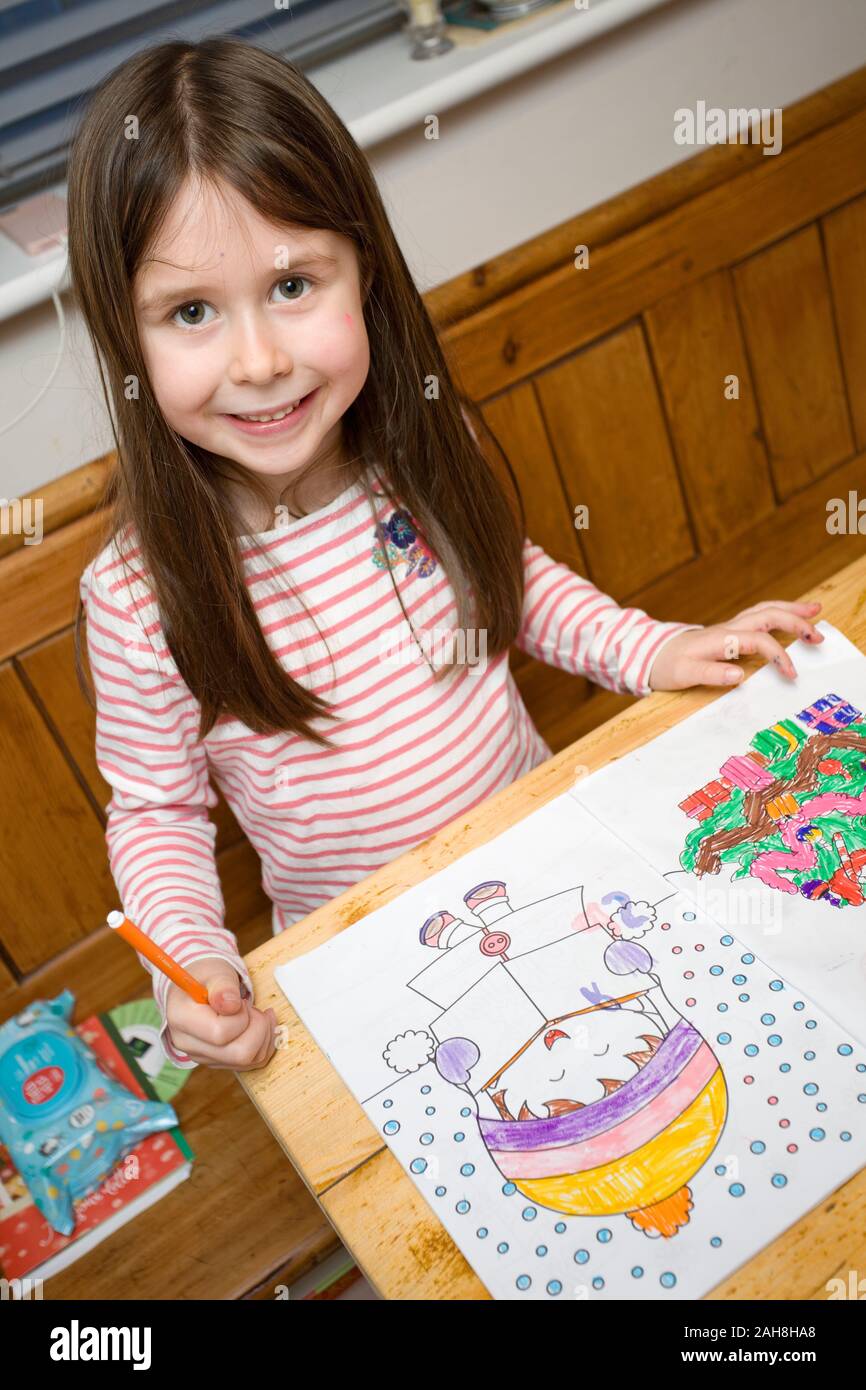 Happy child colouring in pictures at table Stock Photo