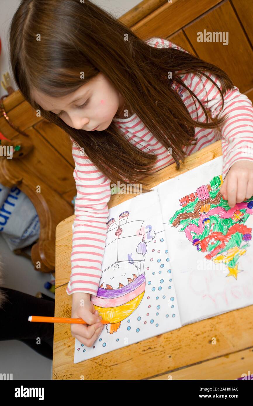 6 year old girl colouring in Christmas scenes in a book Stock Photo