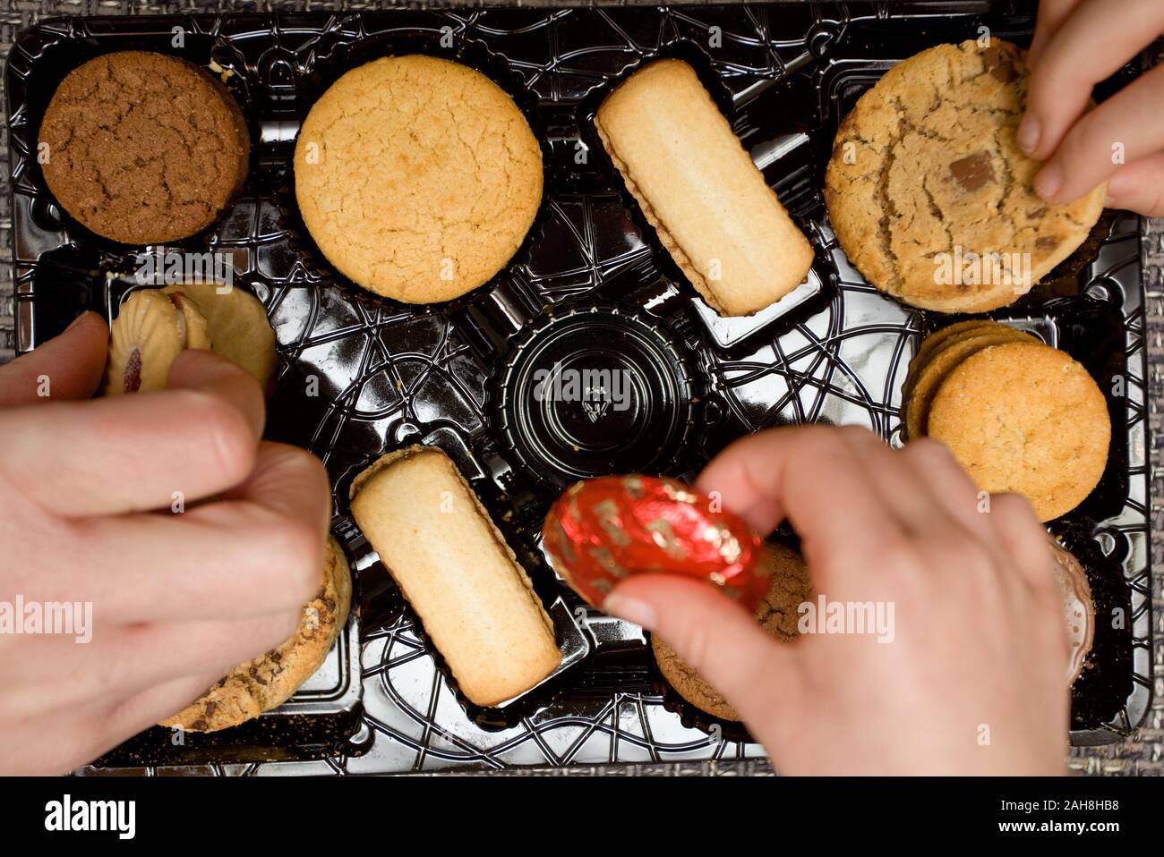 Hands picking out favourite biscuit assortments Stock Photo