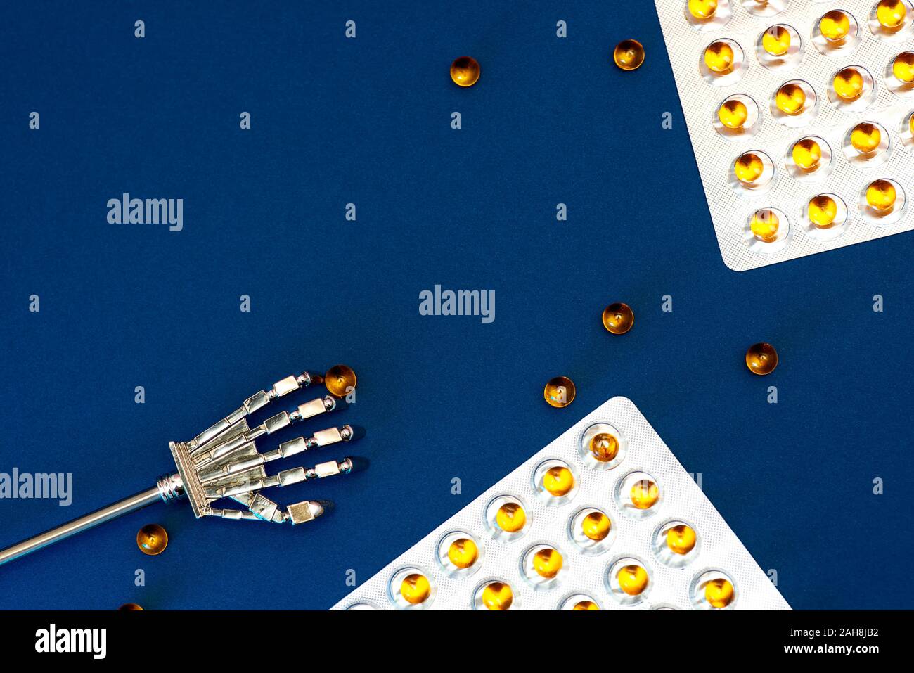 Robot arm and blisters with scattered vitamins with fish oil. Against a