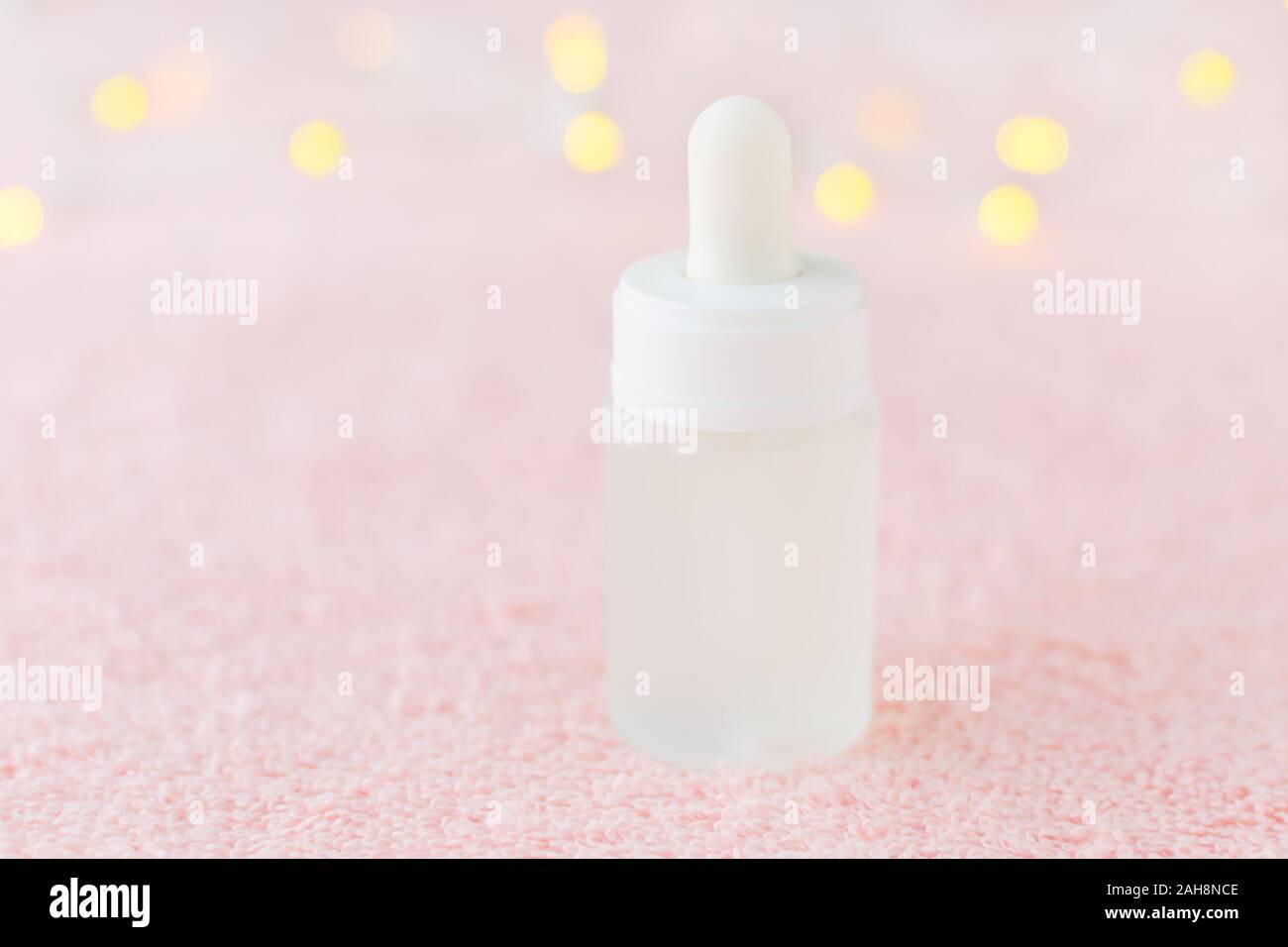 natural face serum in a glass bottle on pink background with bokeh, soft focus Stock Photo