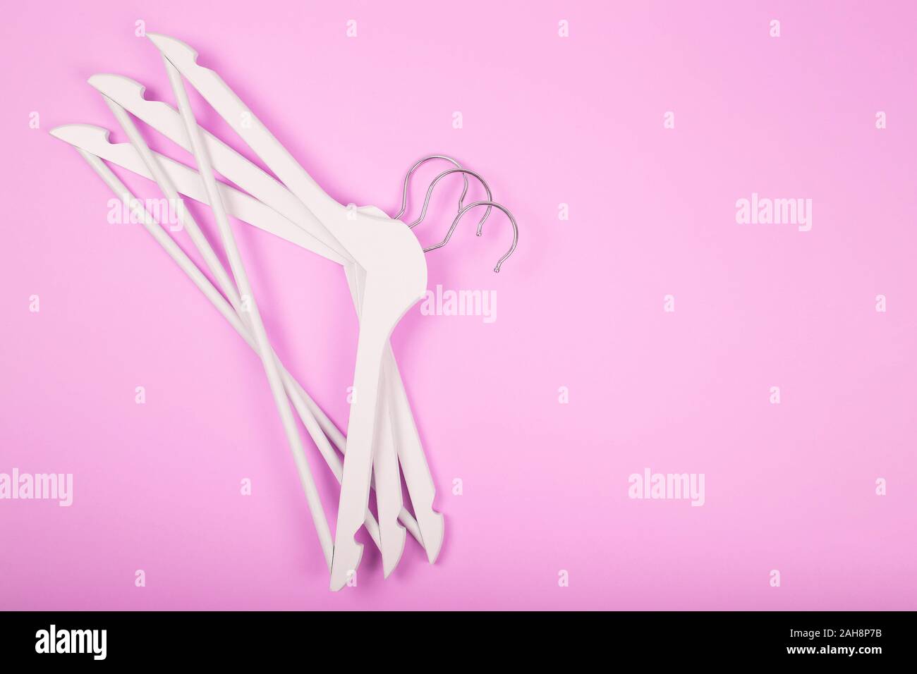 White wooden clothes hanger on pink background Stock Photo