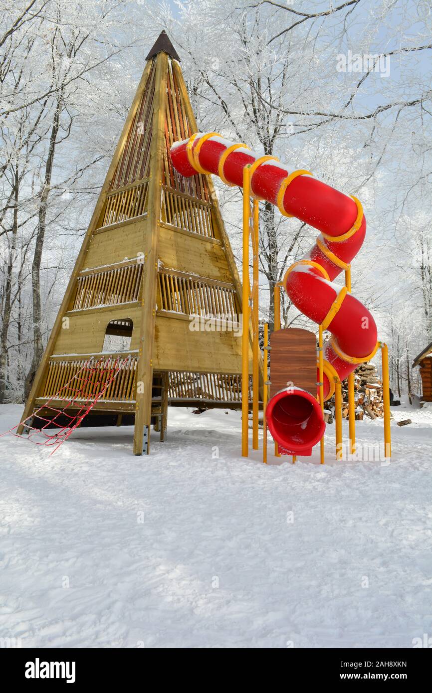 Big toboggan with wooden pyramid shaped base and red twisted tube on