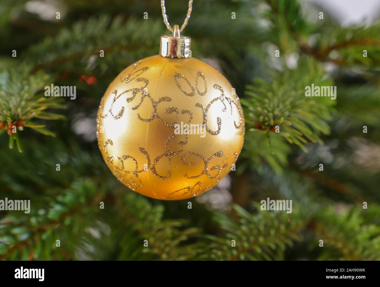 a yellow christmas bauble is hanging on a fir branch of a christmas tree Stock Photo