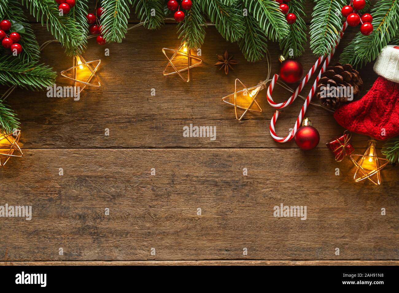 Holiday Christmas card background with festive decoration ball, stars, snowflakes, gift box, pine cones on a wood background from Flat lay, top view. Stock Photo