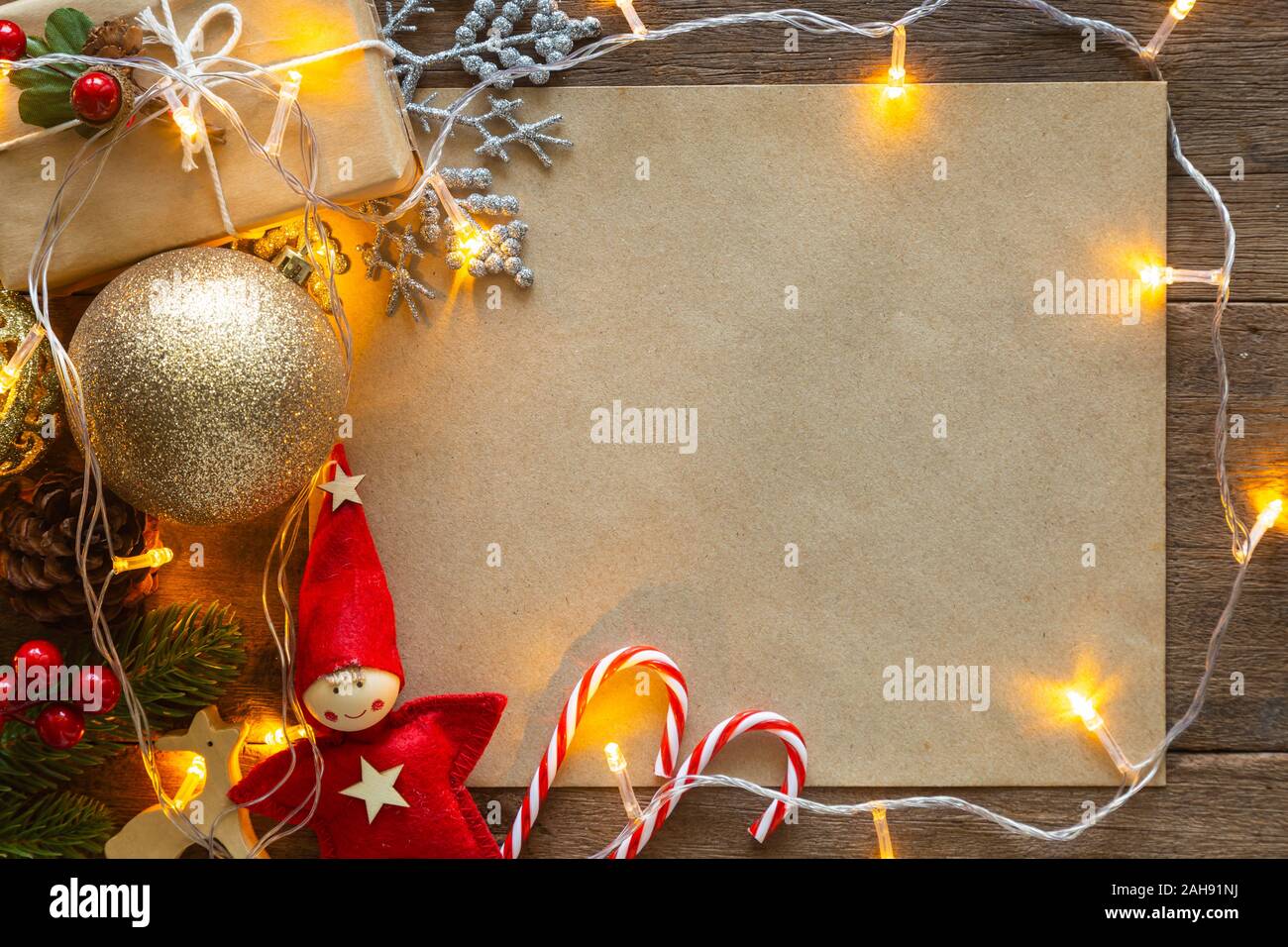 Holiday Christmas card background with festive decoration ball, stars, snowflakes, gift box, pine cones on a wood background from Flat lay, top view. Stock Photo