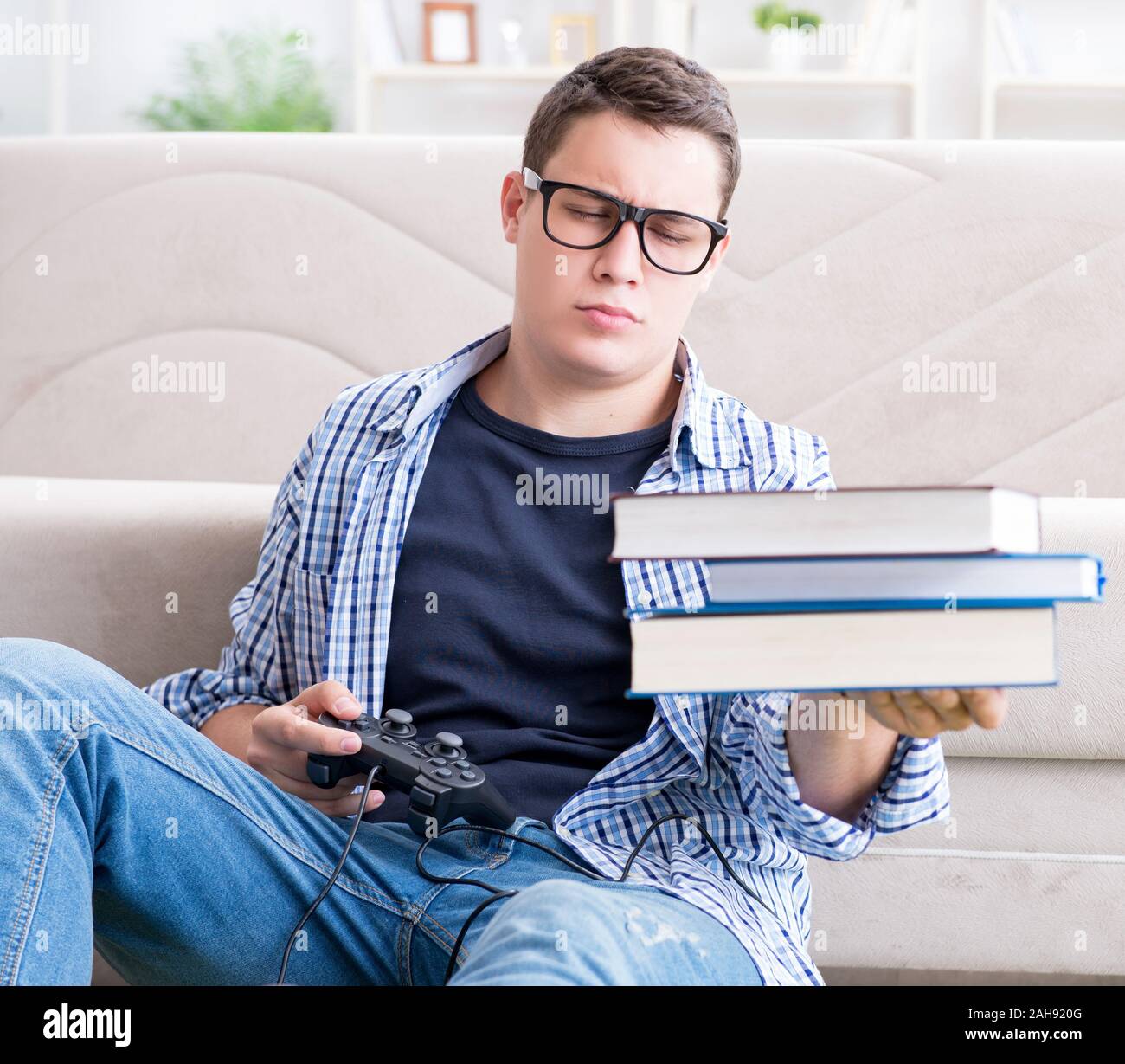 The young student trying to balance studying and playing games Stock ...