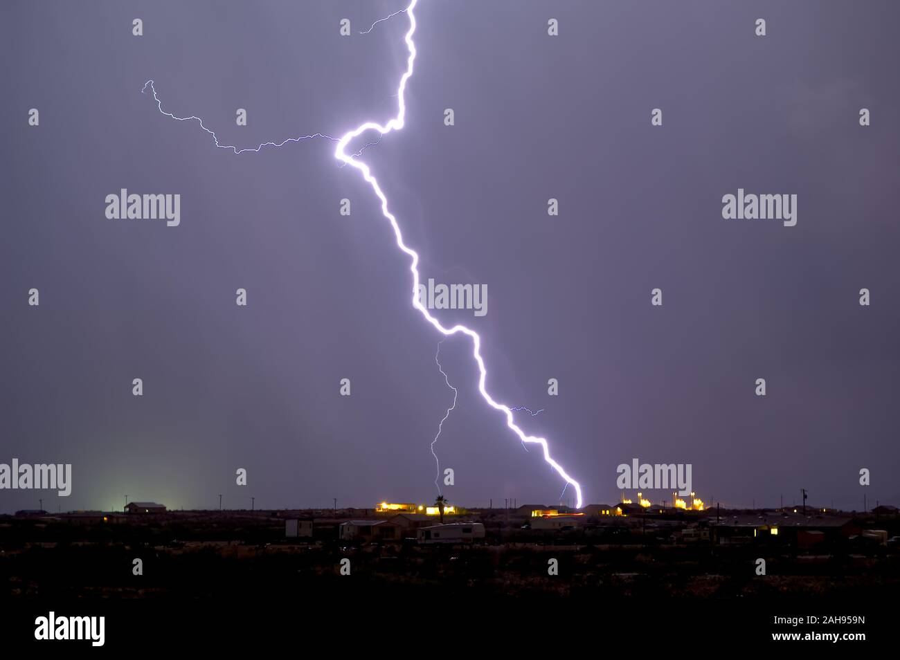 A bright lightning bolt striking near a power plant in Arlington Arizona during the 2012 Monsoon season. Stock Photo