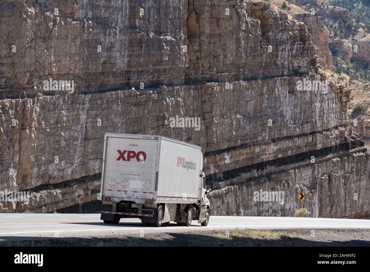 Trucks driving through a road cut with coal seams on Highway 6 in Carbon County, Utah. Stock Photo