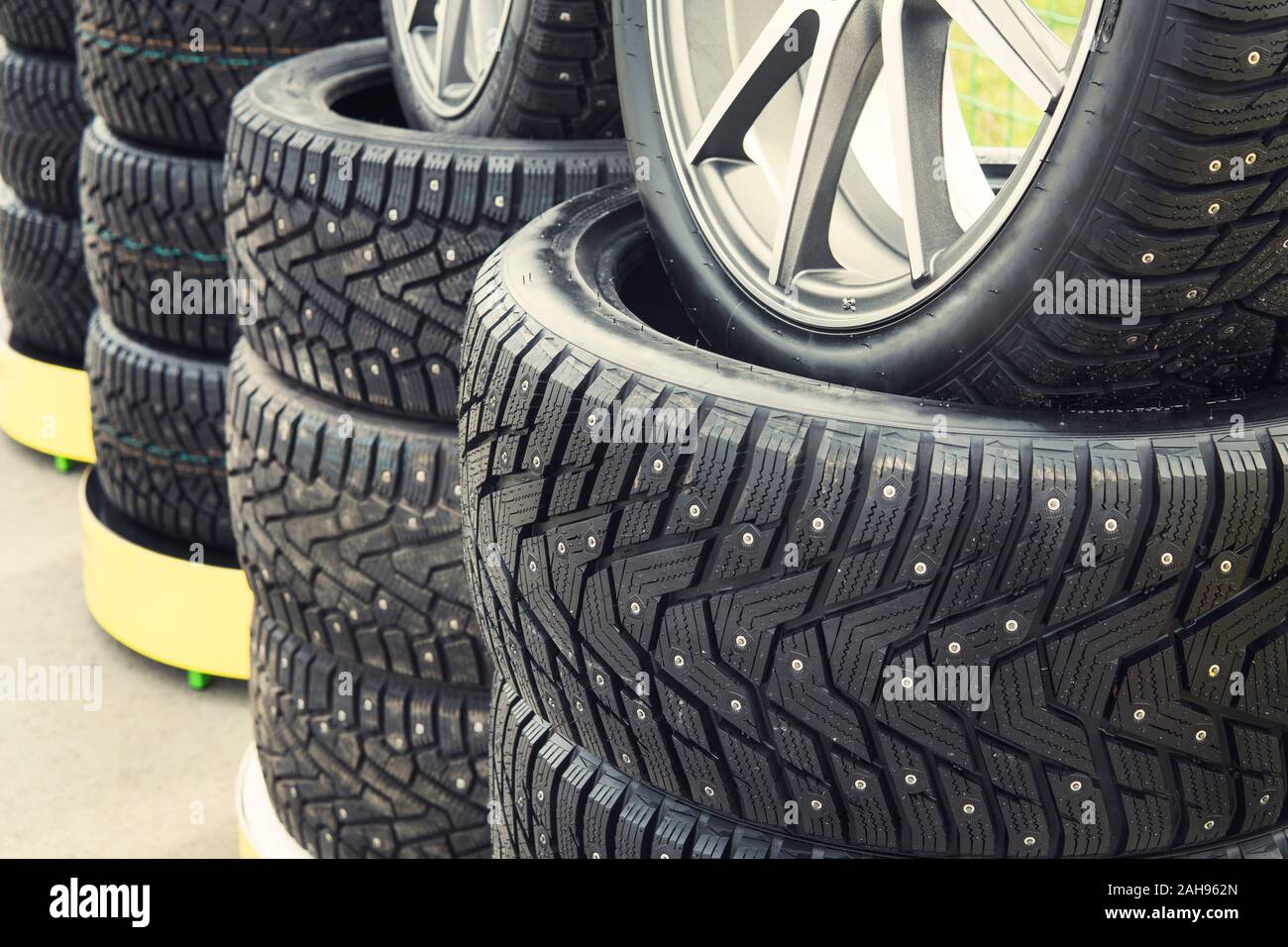 A close up of a lined winter studded wheels set for sale. Close up of the studs and protector on tires installed on the street. Winter tires positione Stock Photo