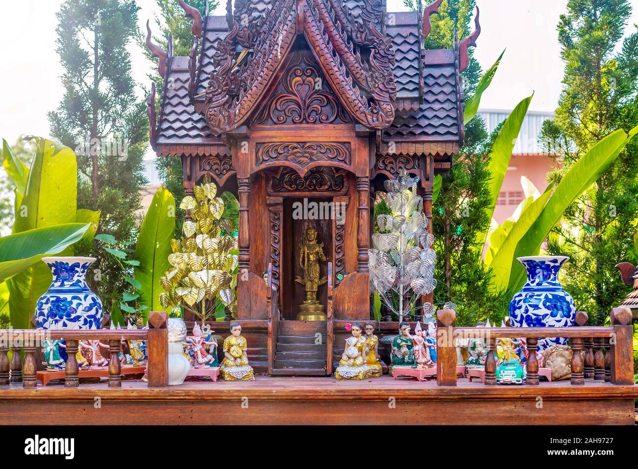 A Thai spirit house, a small replica of a traditional structure, where the deity or spiritual guardian of the property lives and offerings are made. Stock Photo