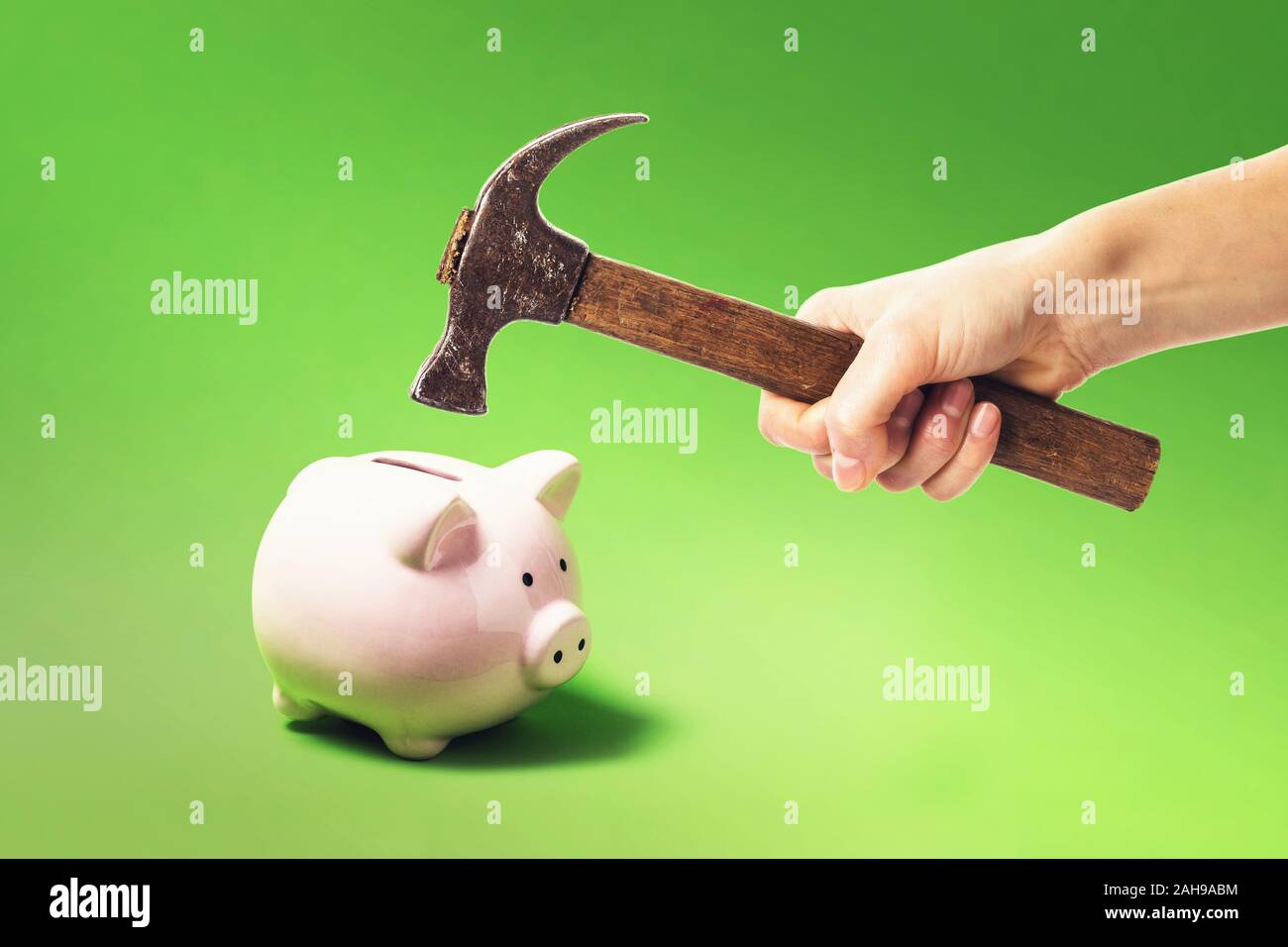 Hand with a hammer smashes a piggy bank. Money shortage concept Stock Photo