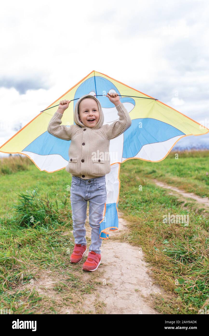 little boy in sweater smiles happy, cheerful and joyful. Launches kite. Emotions of pleasure and