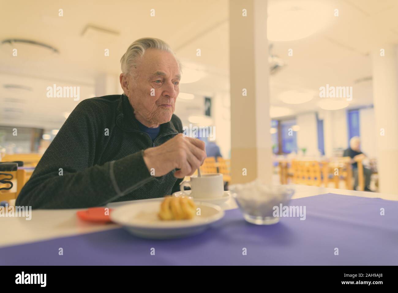 Senior man eating at the cafeteria in nursing home Stock Photo