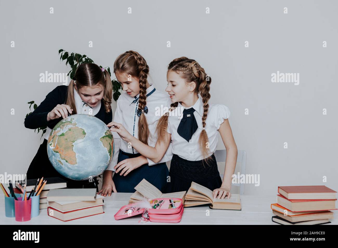 three girls in the school geography lesson learn globe knowledge Stock ...