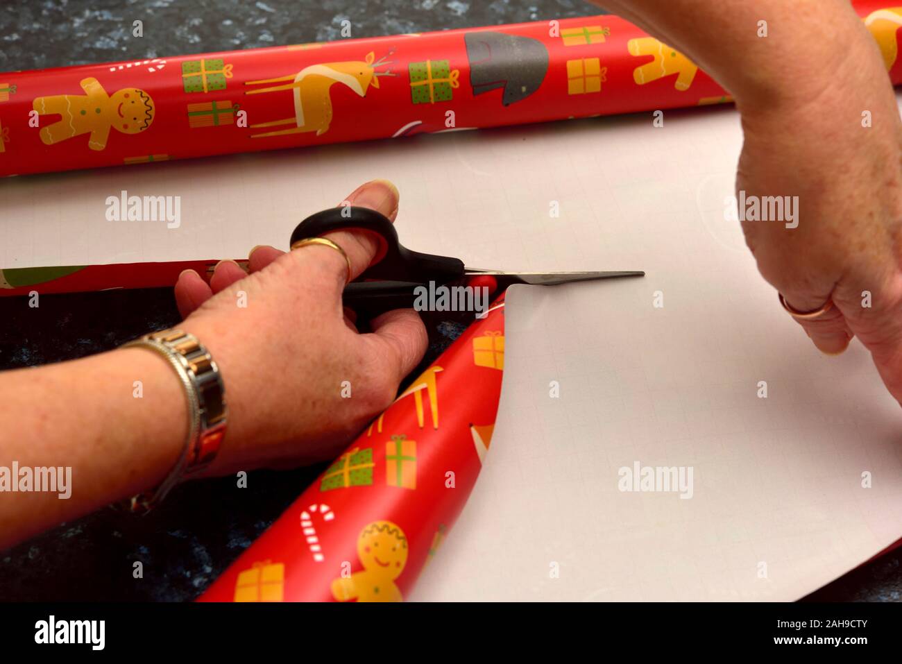 Woman's hands using scissors to cut Christmas wrapping paper Stock Photo -  Alamy