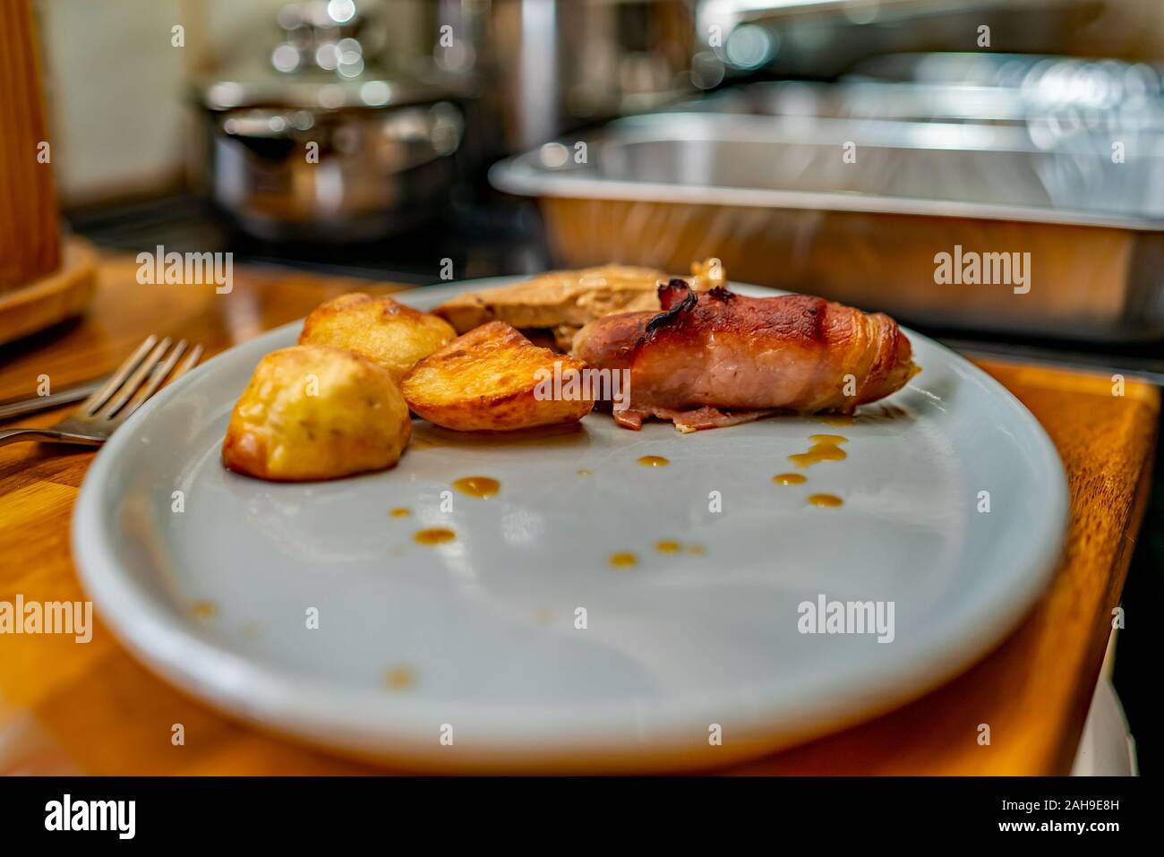 Close up and selective focus of roast potatoes, pig in blanket and roast turkey on a blue oval dinner plate Stock Photo