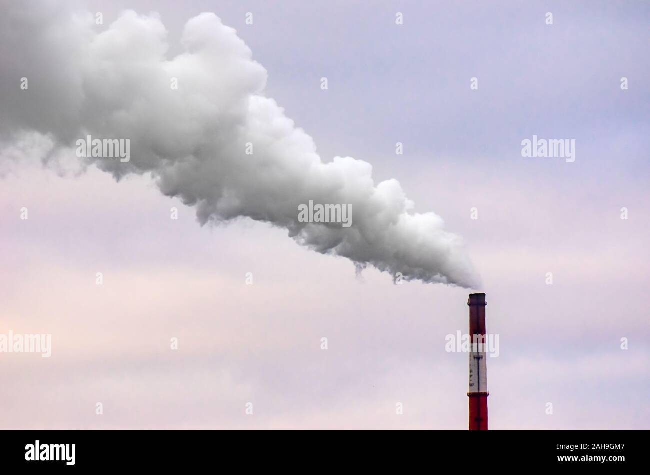 Smoking Tall Industrial Chimney on a Windy Overcast Day. Stock Photo