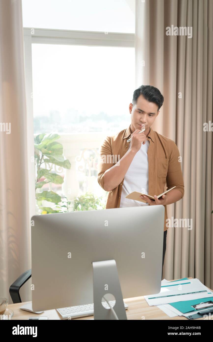 Asian executive aged 25-35 at the desk. He is thinking of a new marketing plan carefully. Stock Photo