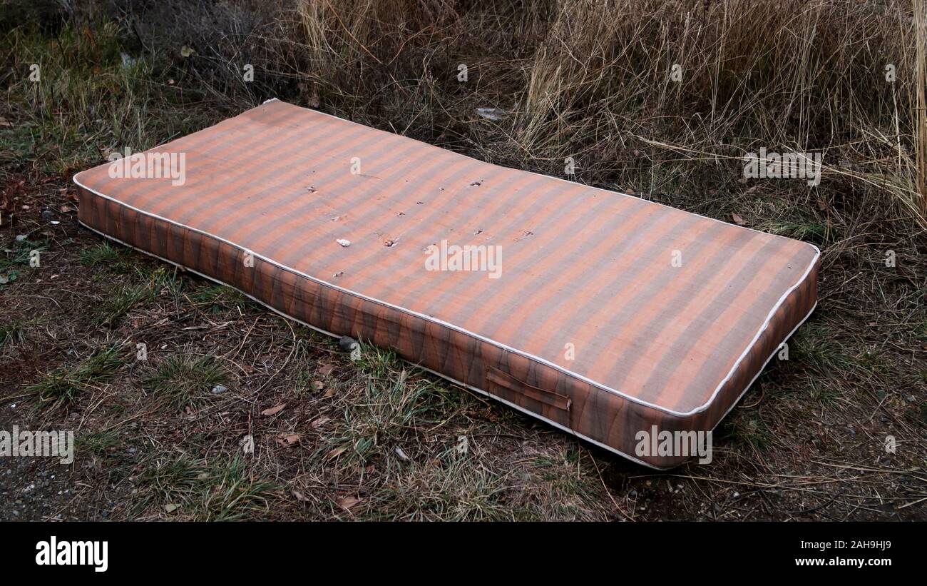 Old mattress on the ground. Striped mattress. Stock Photo