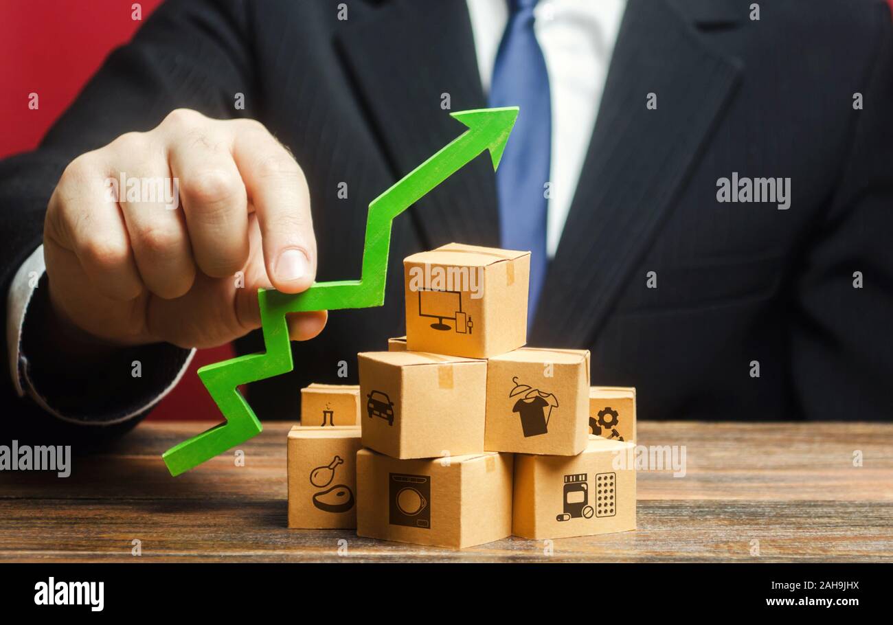 Businessman holding a green arrow up over boxes. Tactics and strategy, marketing. Value added goods. Boost sales rate. Increasing production of goods, Stock Photo