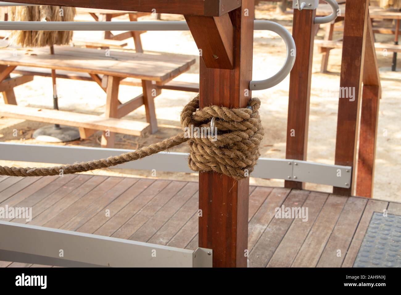 Heavy thick rope tied to thick wooden post with timber floor in ...