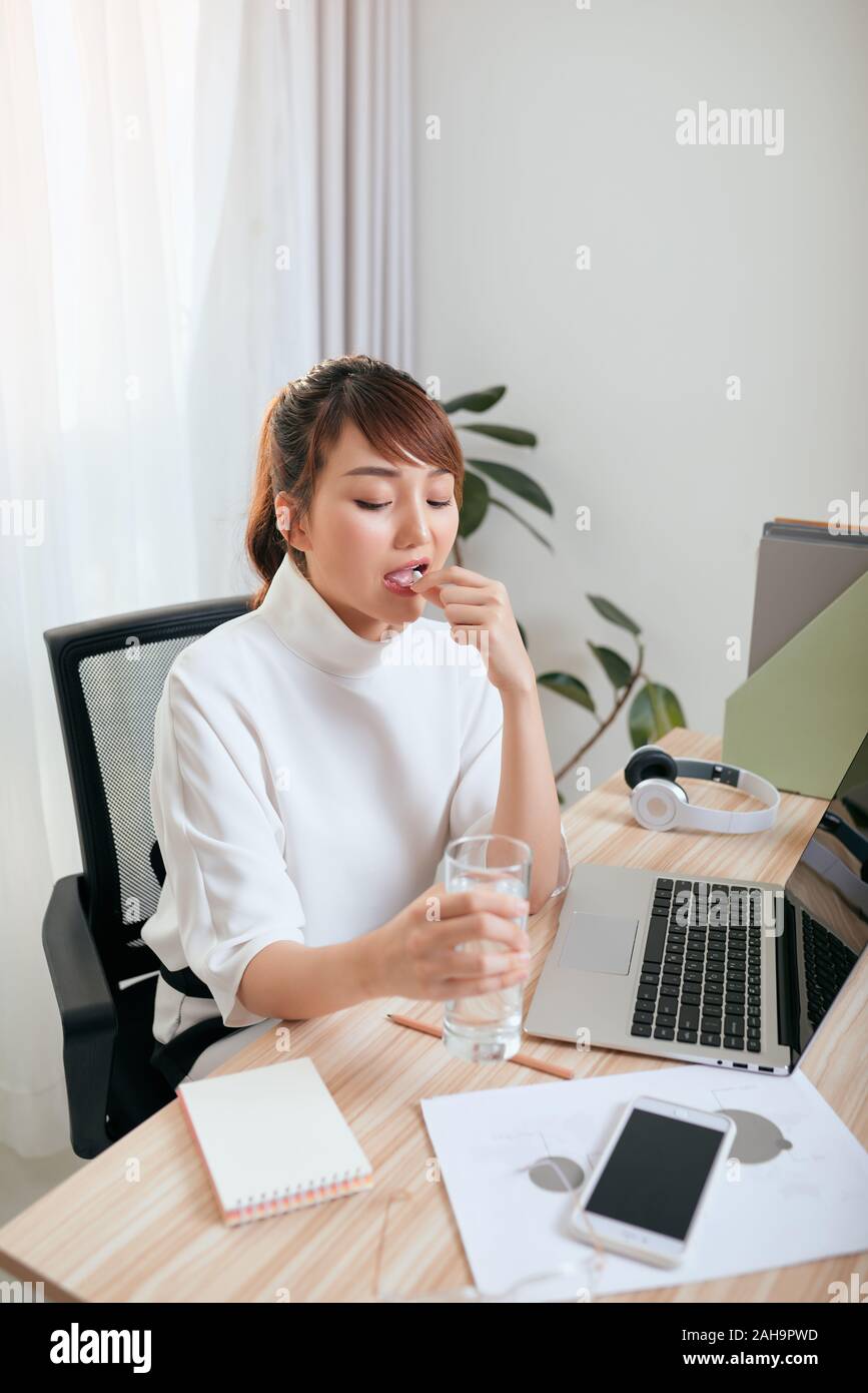 Business woman drinking water and taking medicine. She feels like sick Stock Photo