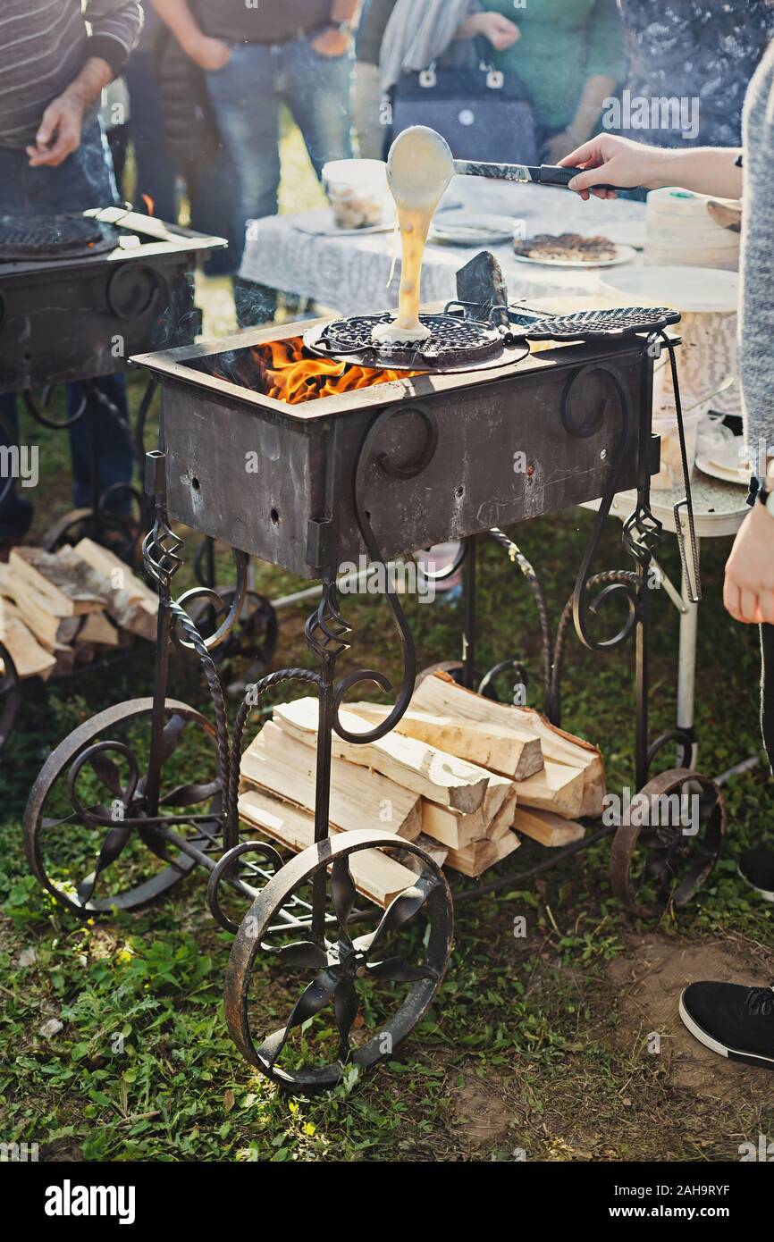 Baking waffles on open flame outdoors in a hammered cast iron grill