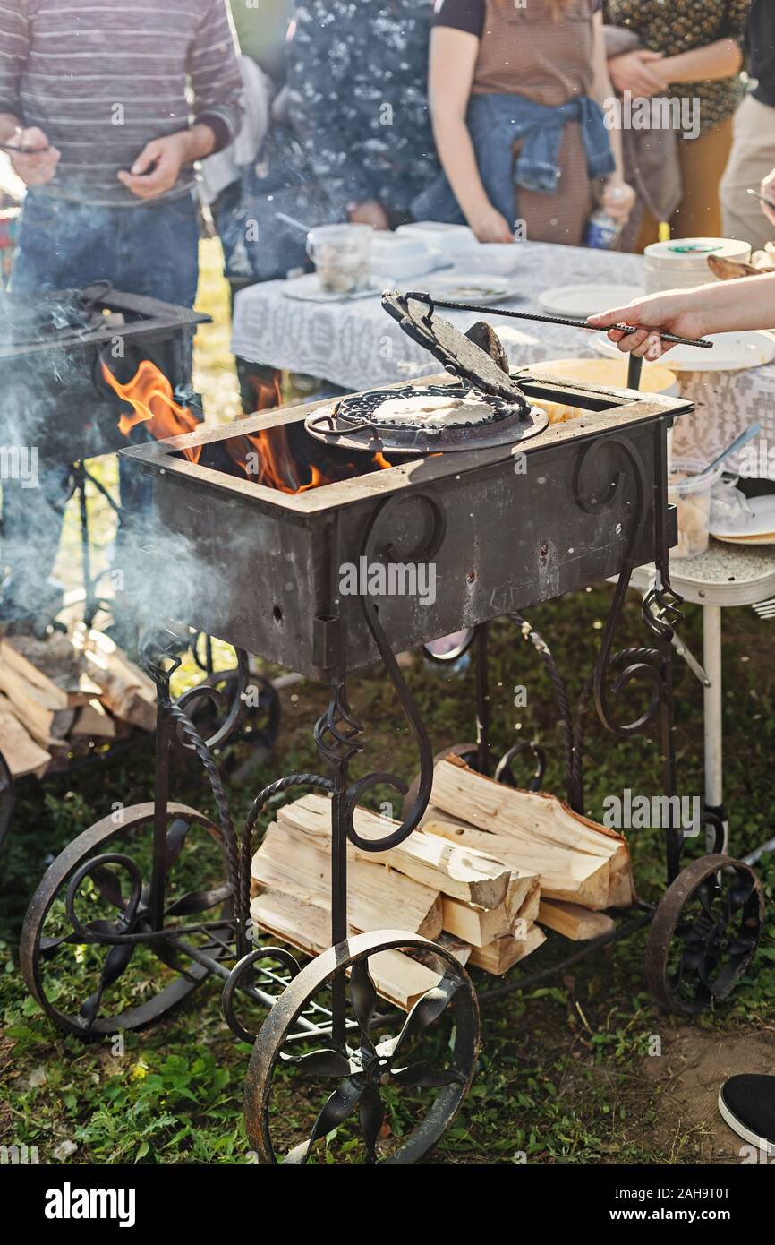 Baking waffles on open flame outdoors in a hammered cast iron grill