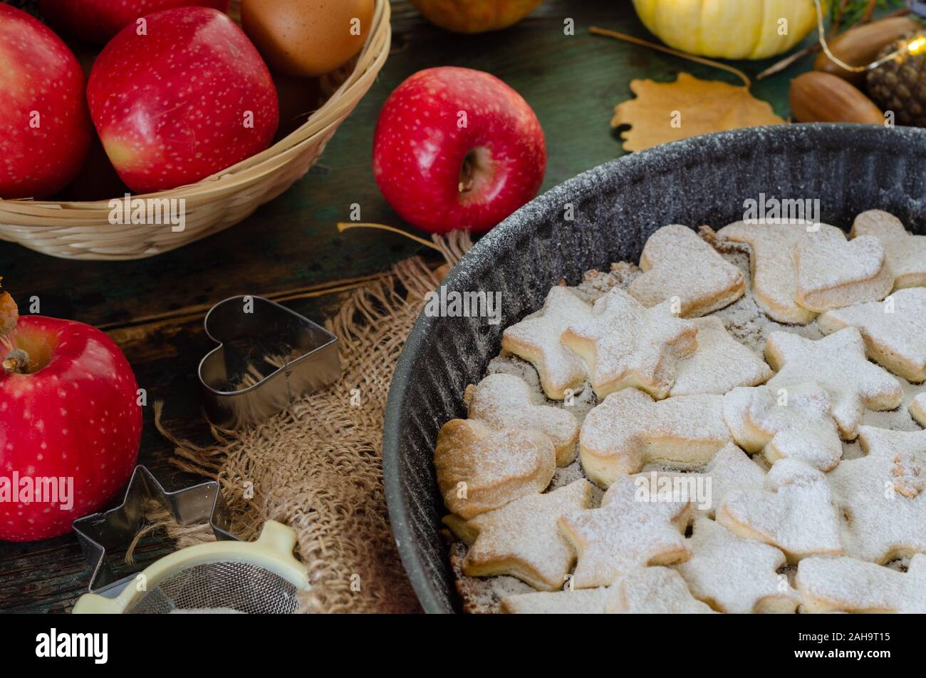 Fresh baked homemade apple pie on a wood table with cutter and apples. Stock Photo