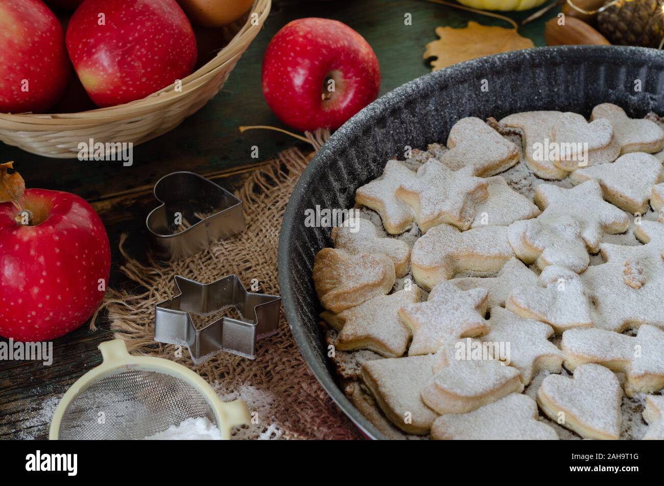 Fresh baked homemade apple pie on a wood table with cutter and apples. Stock Photo