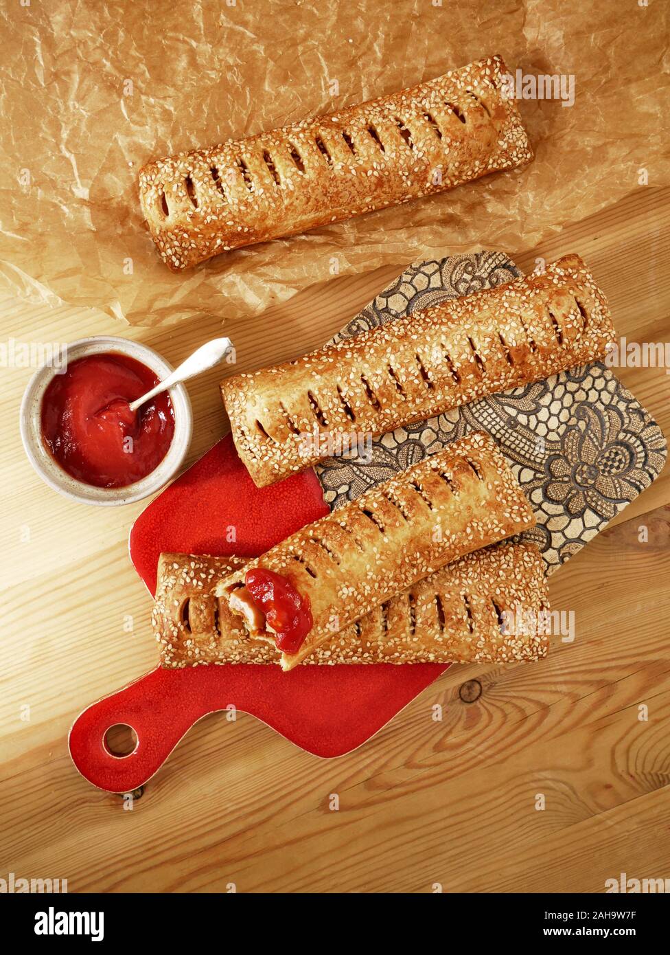 Homemade mini hot dogs with sausage, sesame seeds and fresh tomato