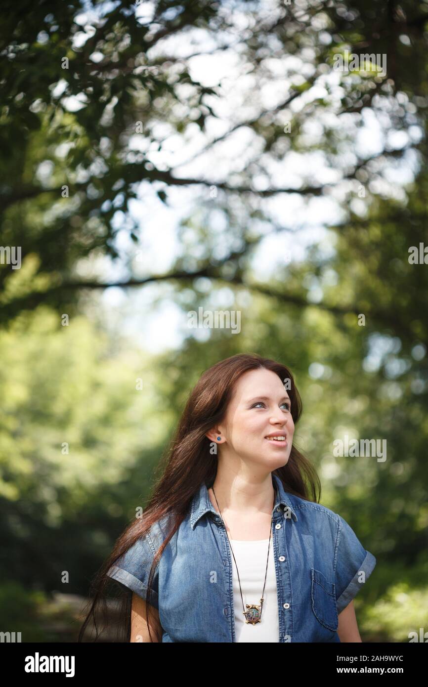 Young smiling brunette woman walking outdoors in park Stock Photo