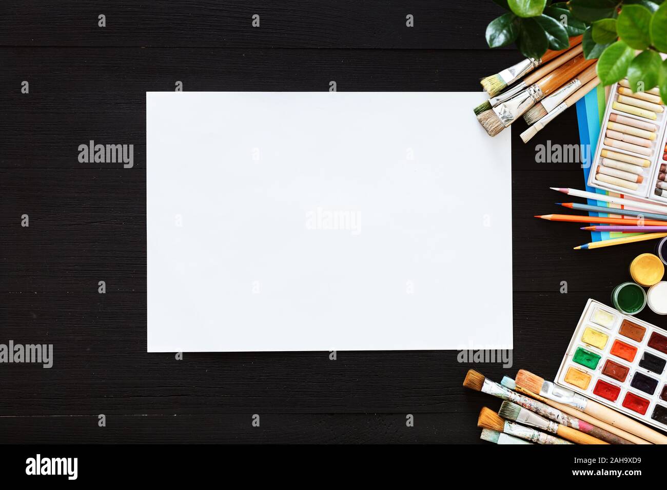 Creative paint background supplies paper brushes paintbox on black wood desk Stock Photo