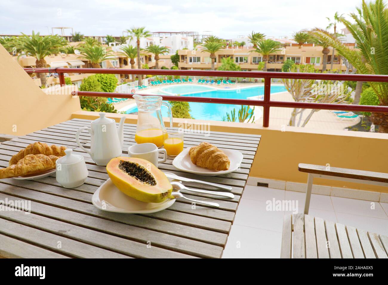Hotel room breakfast on balcony view of swimming pool and palm trees. Vacation travel morning food breakfast in luxury resort outside. Stock Photo
