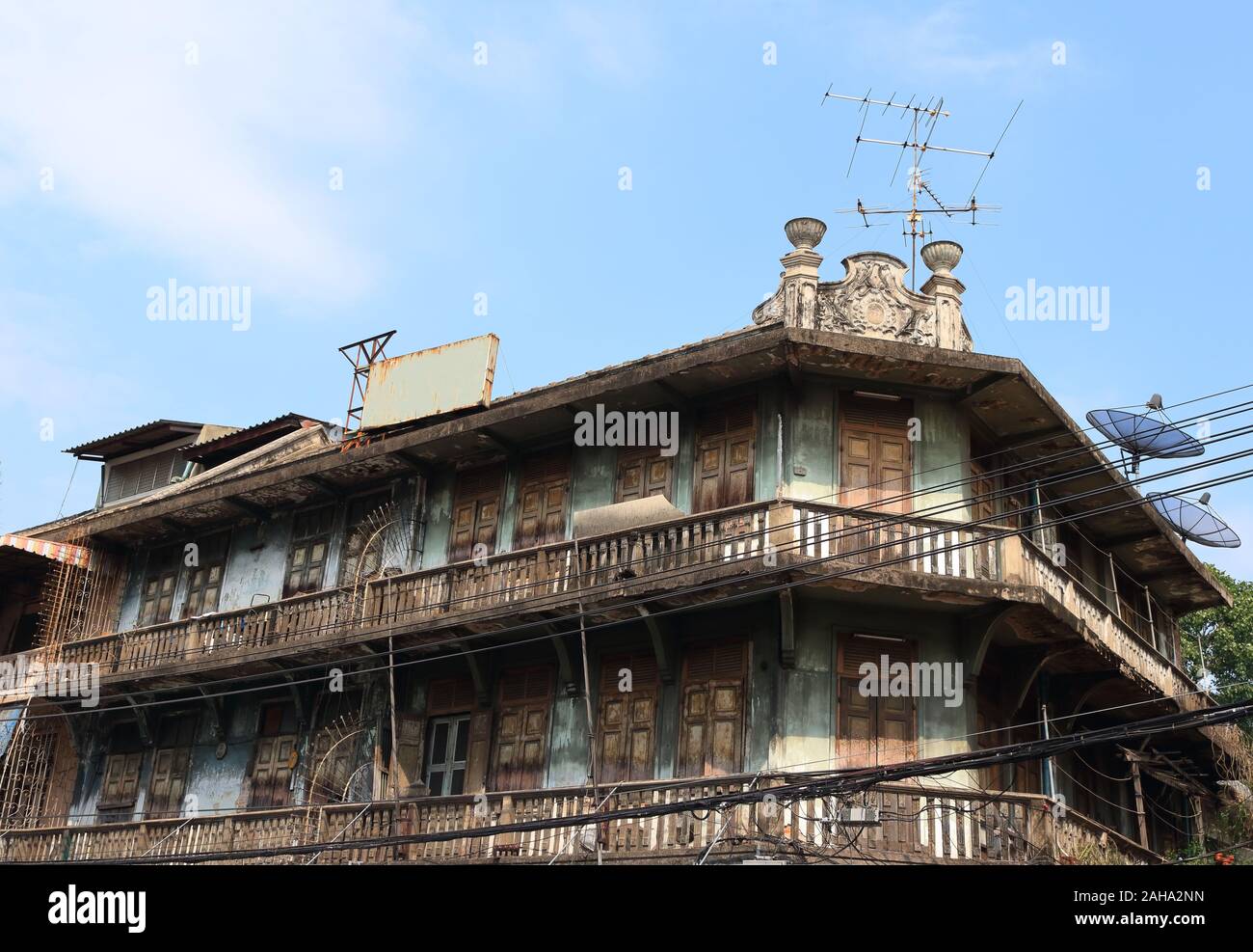 Exterior of vintage building with blue sky background, the building has peeling blue wall and wooden doors with long balcony Stock Photo
