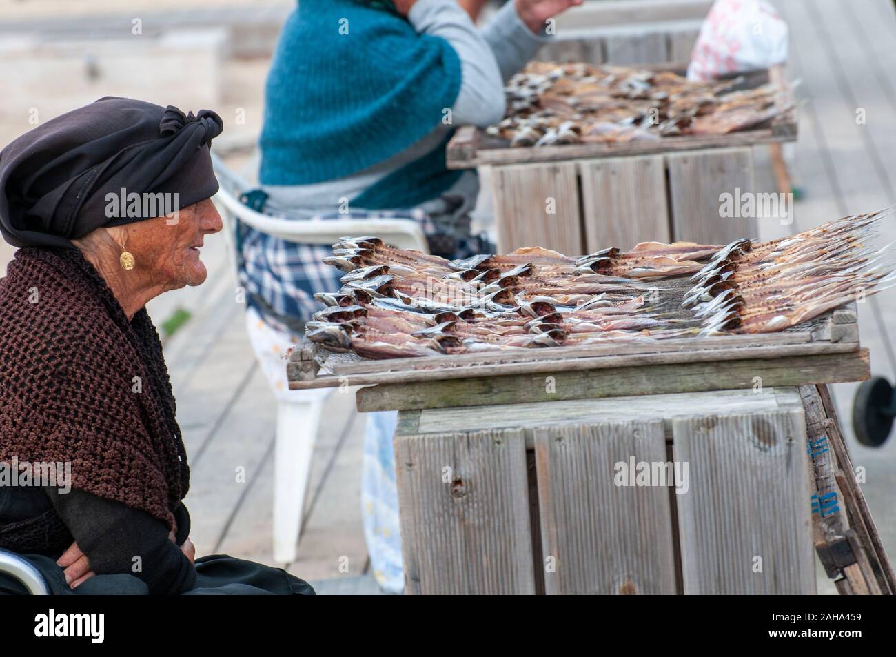 Fishmonger sells sun dried fish on the beach at Nazare, Portugal Stock Photo