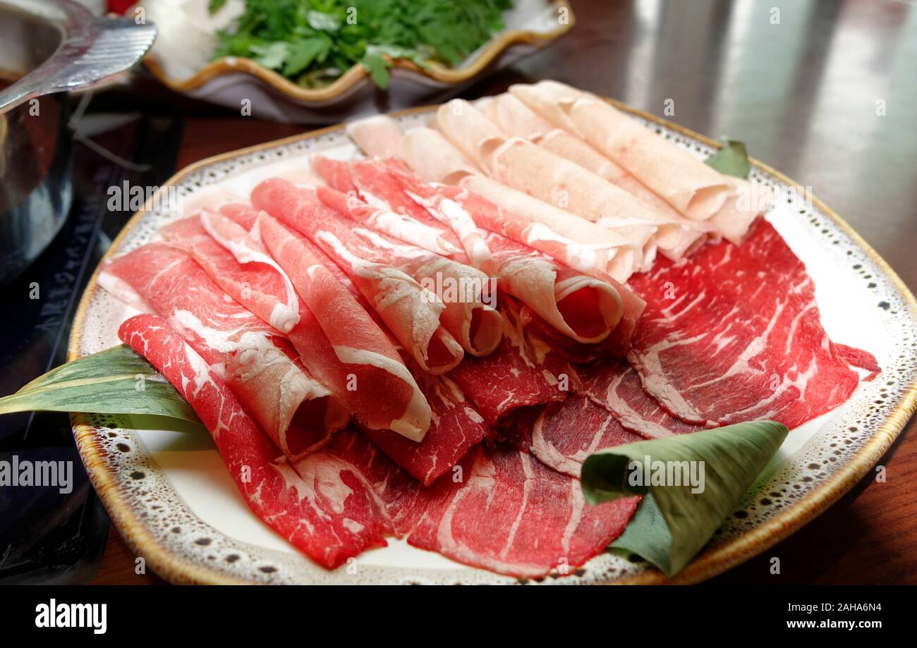 Sliced raw beef for cooking on table with hot pot Stock Photo