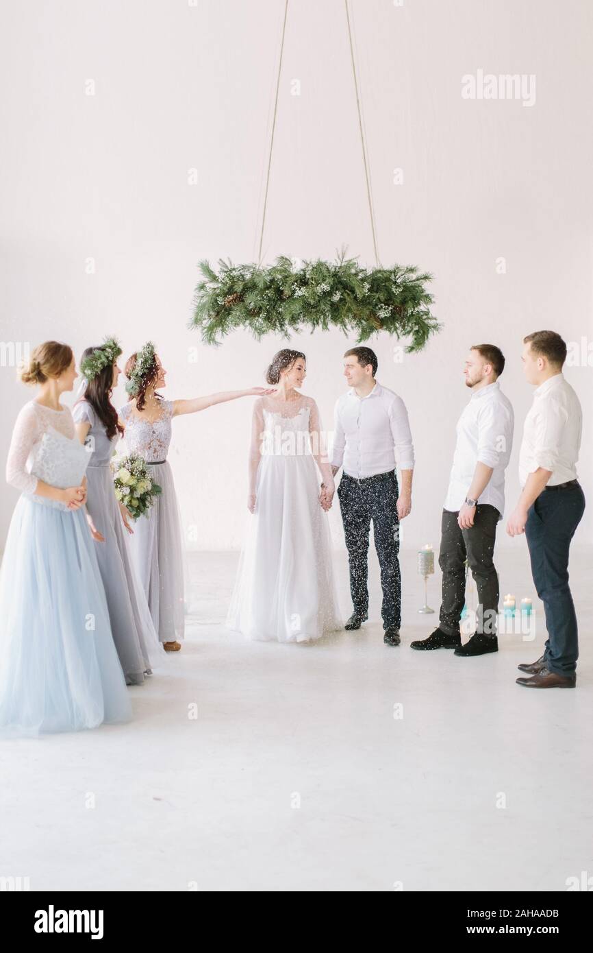 Bride and groom holding the hands of each other in the rain of rice