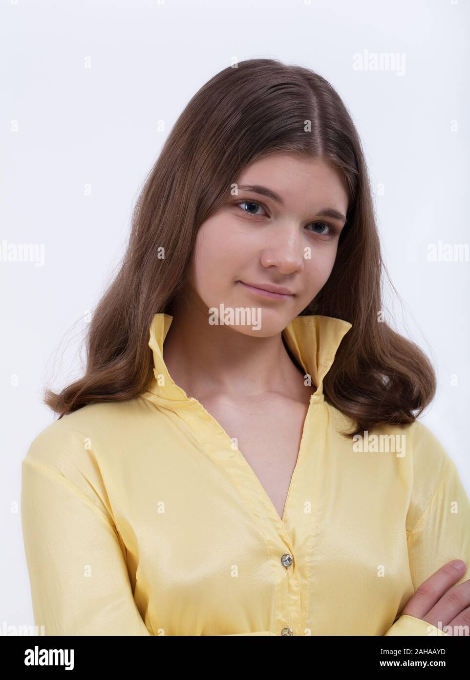 Closeup portrait of a girl with long hair in a yellow blouse with a standing collar on a light background Stock Photo