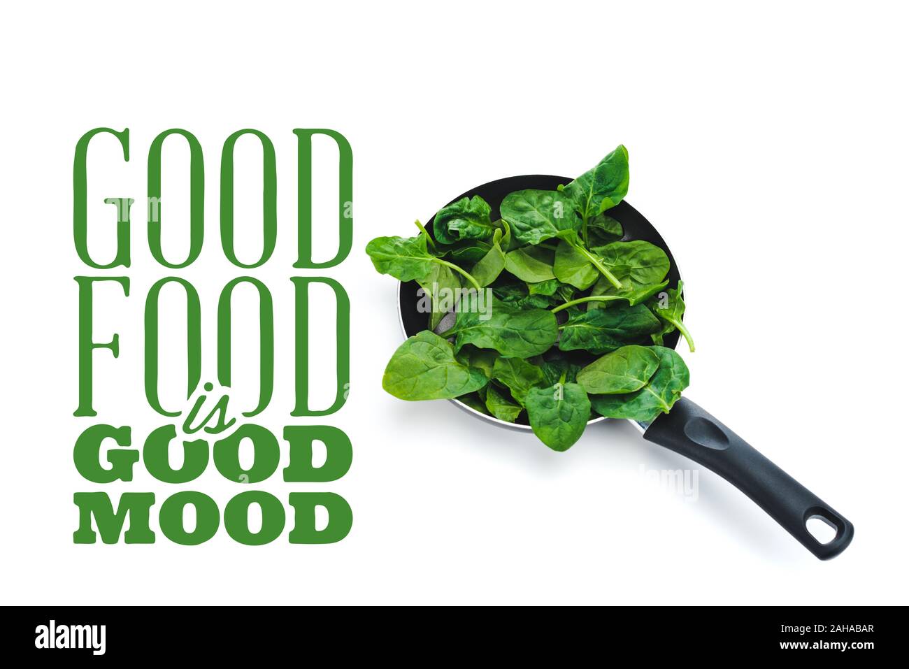 fresh spinach leaves in frying pan on white background near good food is good mood green lettering Stock Photo