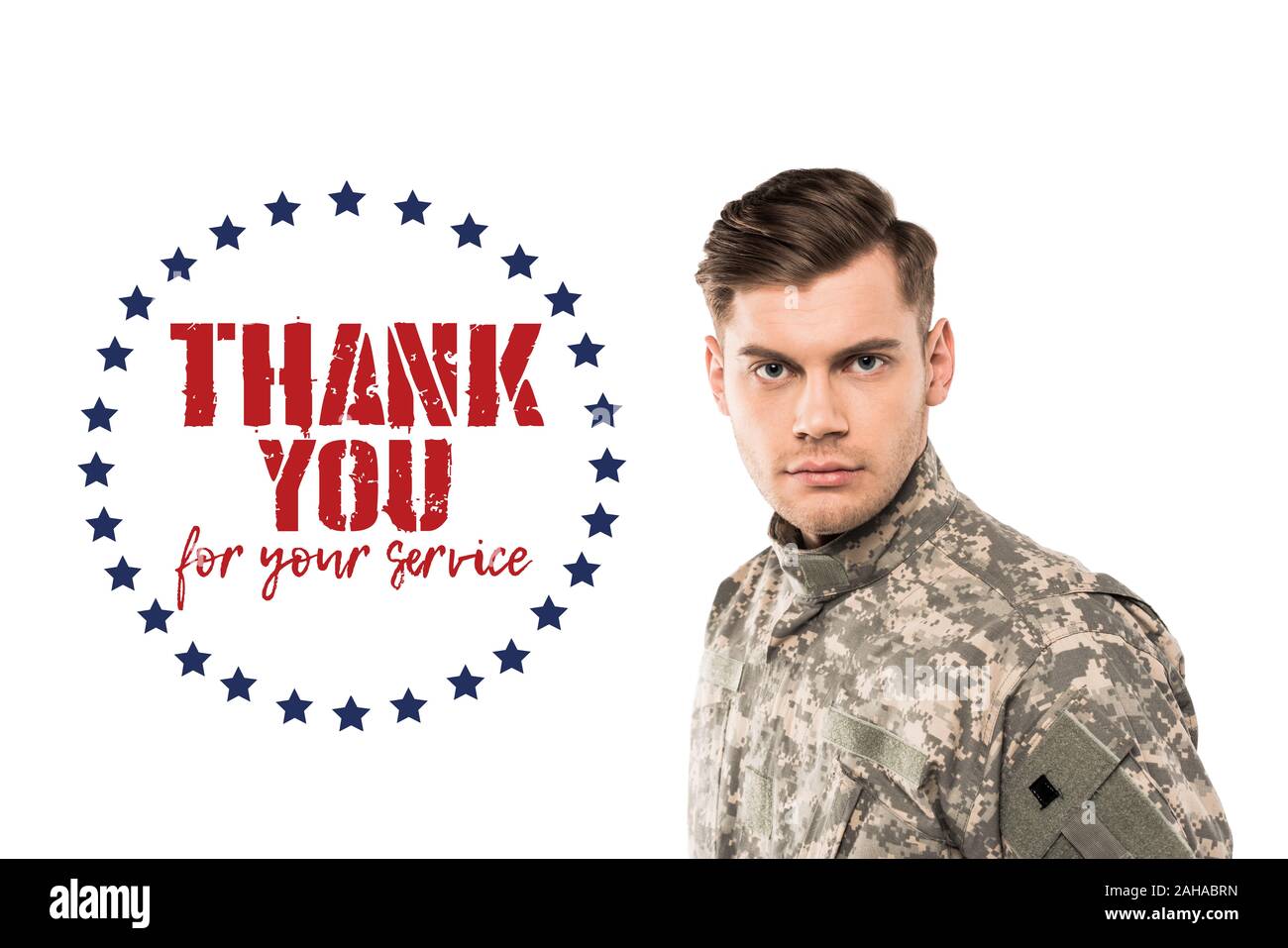 serious and handsome soldier in uniform looking at camera near thank you for your service lettering on white Stock Photo