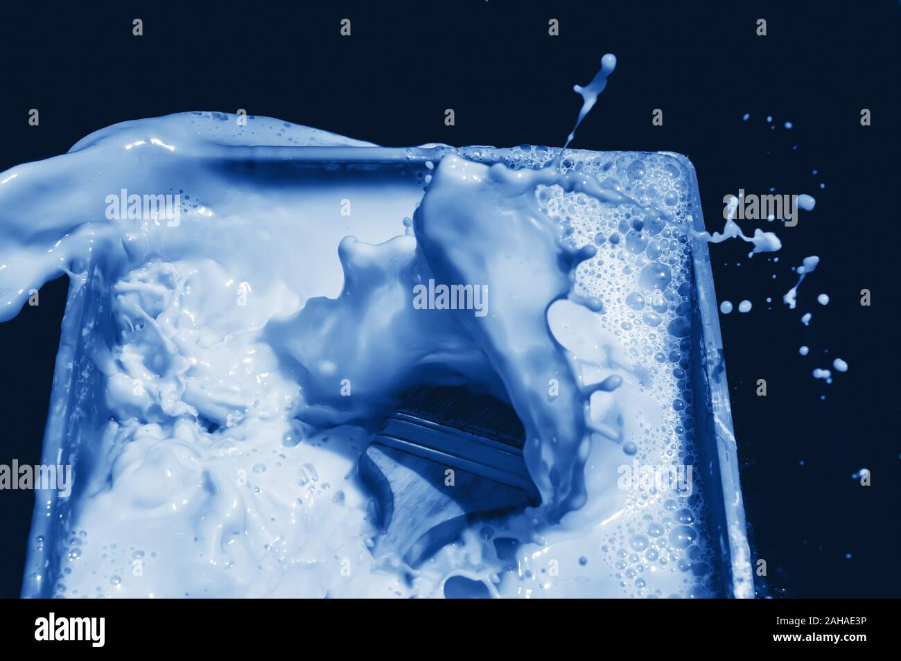 Blue splash after brush falling into fluid paint on black background. Scene toned in trendy classic blue - color of the year 2020 concept. Dynamic bac Stock Photo