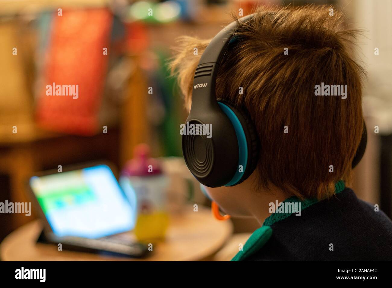 A three year old child watching a tablet or mobile device wearing headphones Stock Photo