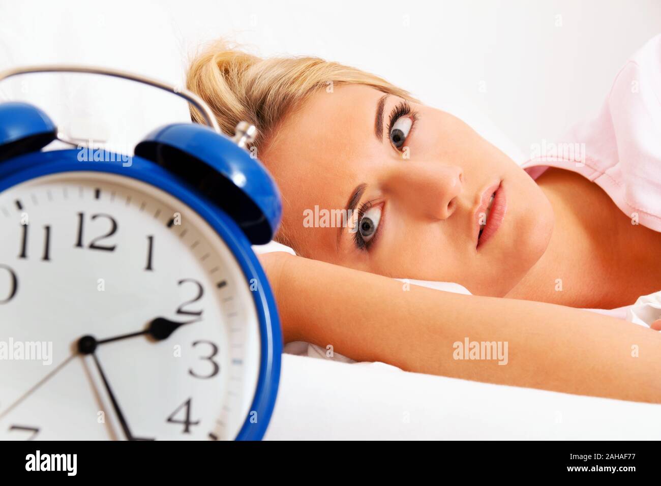 Junge blonde Frau leidet an Schlaflosigkeit, Wecker zeigt 2.25 am, Uhr, MR: Yes Stock Photo