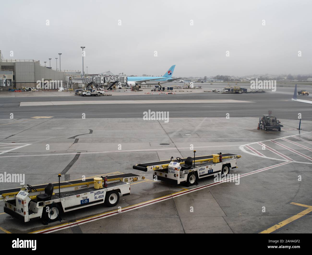 Two airport conveyor trucks in the foreground with a jet in the background. Stock Photo